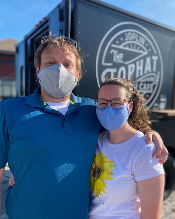 collin standing with his arm around a pretty girl while they both wear masks